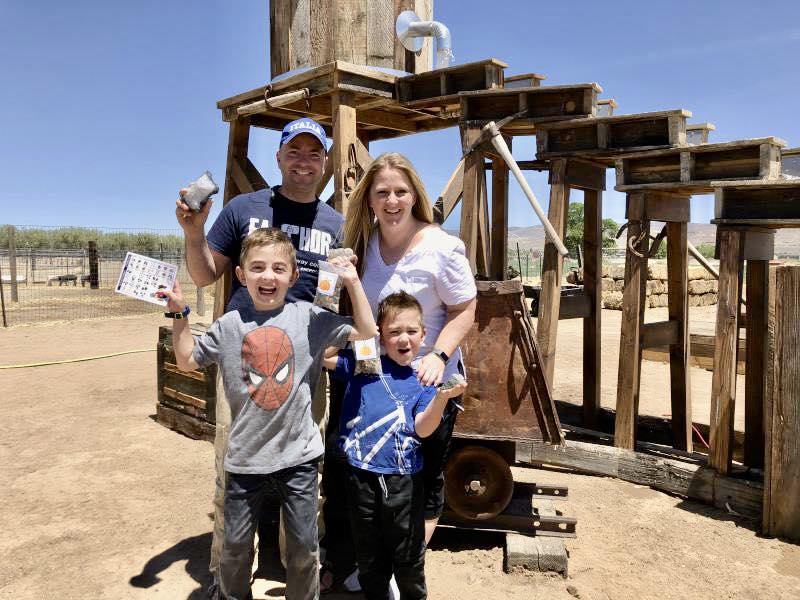 An excited family holding their bags of gems in front of the gem mining sluice.